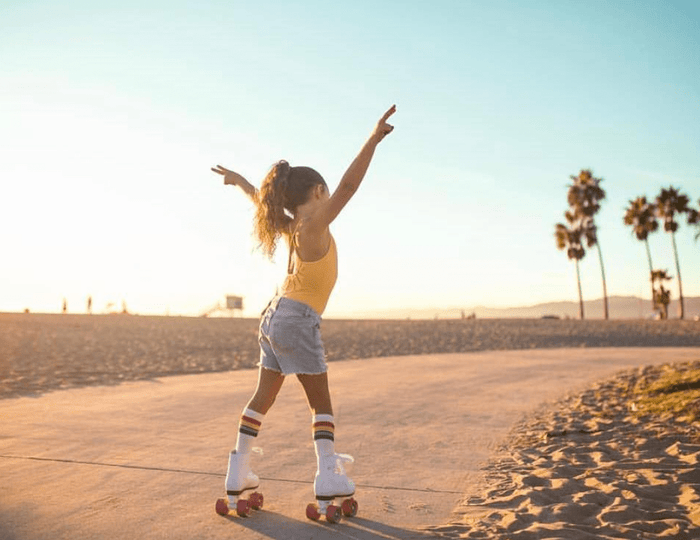 3 Pairs of Any Under the Knee Rainbow Striped Tube Socks by Pride Socks on the beach with roller skates