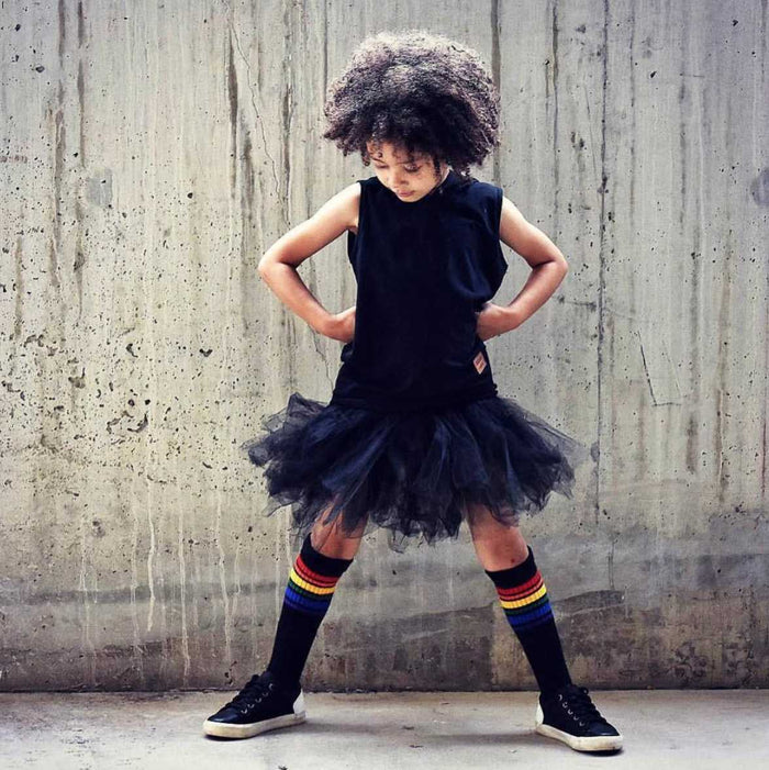 Colorful Brave rainbow socks by Pride Socks while modeling her black dress