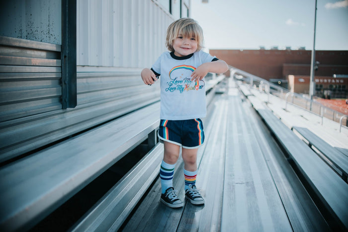 Colorful Courage baby and toddler socks by Pride Socks worn by a toddler on the bleachers