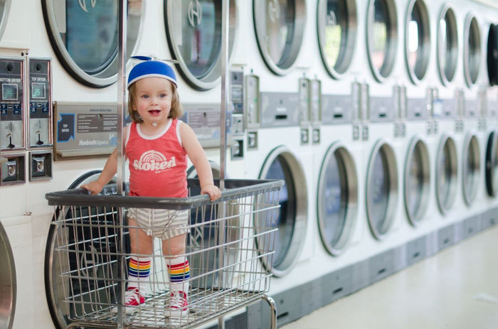 Toddler wearing Fearless rainbow tube socks while playing at the laundromat