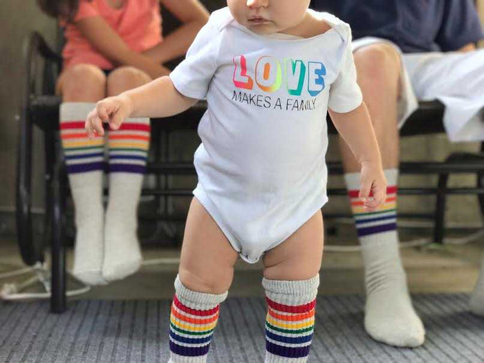 Toddler wearing Happy rainbow tube socks while playing outside with family