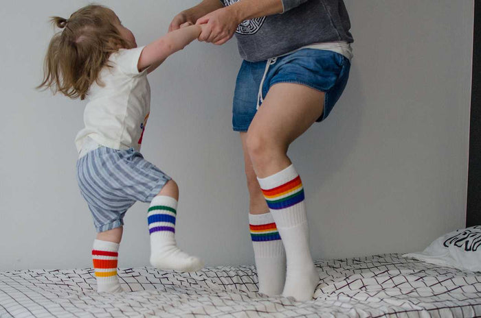 Love rainbow under the knee tube socks with retro rainbow stripes with mom and son jumping on the bed